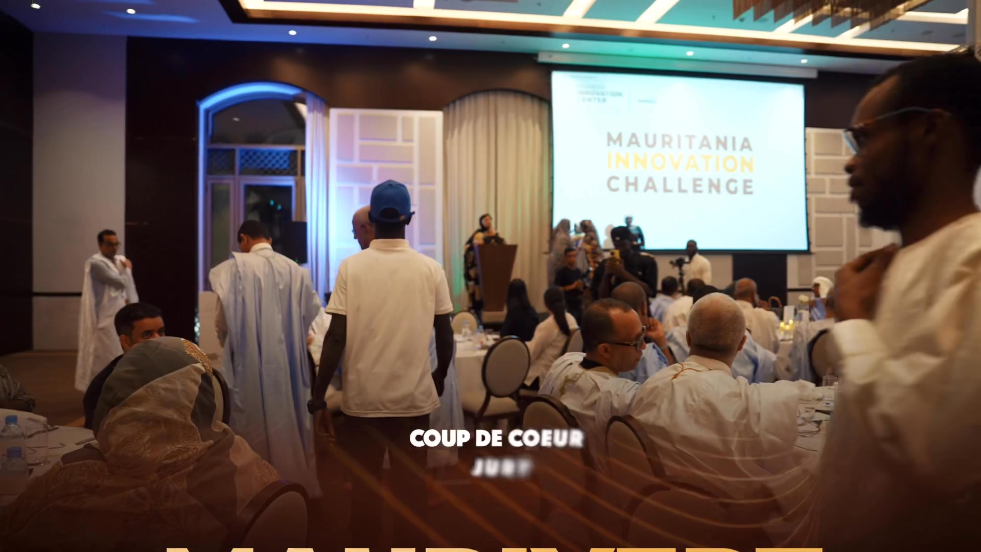 An event hall and stage with the Mauritania Innovation Challenge screen, from LINC’s film for Kosmos Innovation Center.